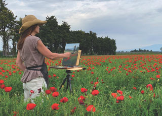 Artist Jane Hunt painting en plein air in a poppy field.