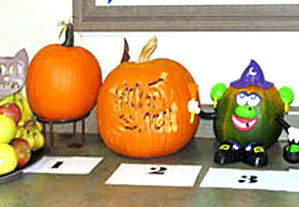 three pumpkins on a counter, one with Halloween painting, one carved, and one untouched